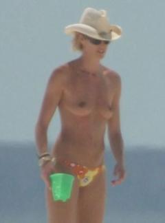 Elle Macpherson topless in a hat on a beach