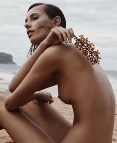 Mali Koopman sittinf sitting naked on a beach