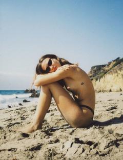 Reda Pilybaite sitting topless on a beach image