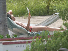 Rebecca Gayheart reading topless on a beach