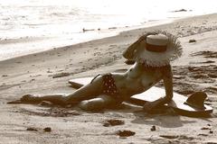 Brooke Burke lying topless on a beach