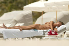 Manuela Arcuri lying topless on a beach