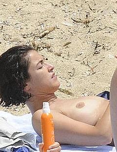 Blanca Romero sunbathing topless on a beach