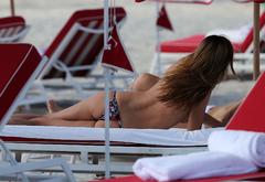 Alina Baikova sunbathing topless on a beach