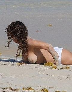 Brooke Burke topless on a beach in white pants