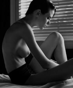 Antonella Bertola sitting topless on a bed