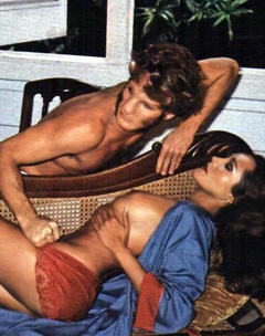 Barbara Carrera topless on a sofa