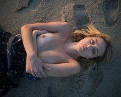 Dagny Paige lying topless on a sand