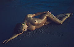 Marisa Papen lying naked on a beach