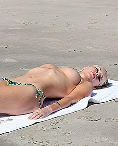 Sophie Monk lying topless on a beach