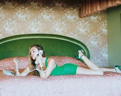 Miley Cyrus in short green dress lying on a bed
