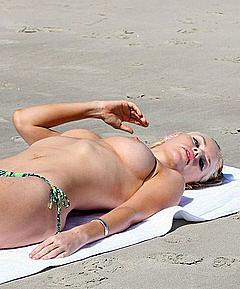 Sophie Monk sunbathing topless on a beach